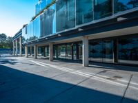 this is an empty street near a modern building with glass windows on the sides and a metal frame on top of the building