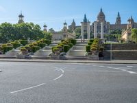 a woman riding on a red bicycle through an ornate garden area in front of some large buildings