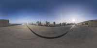 a 360 view lens shot of a skate park, with trees in the background and boats in the water