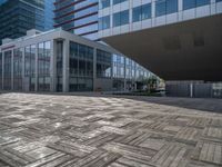 an outdoor patio that has many tiles on it and several buildings in the background with glass