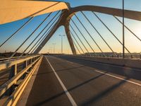 the sun is setting over the road of an empty bridge with multiple columns and metal rails