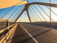 the sun is setting over the road of an empty bridge with multiple columns and metal rails