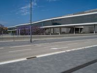 empty city street with buildings in the background with a clear blue sky on one side and two white lines on other