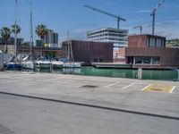 a lot of parking space next to a body of water near a big building under construction