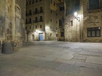 there is an empty courtyard in a big city at night with lights on the buildings