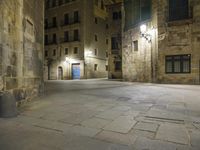 there is an empty courtyard in a big city at night with lights on the buildings