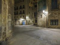 there is an empty courtyard in a big city at night with lights on the buildings