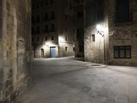 there is an empty courtyard in a big city at night with lights on the buildings