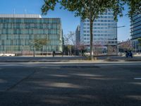 an empty street in front of a building and trees on the other side of the road