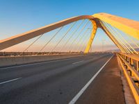 a yellow and white bridge over the water on a clear day with no clouds in the sky