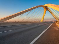 a yellow and white bridge over the water on a clear day with no clouds in the sky