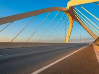 a yellow and white bridge over the water on a clear day with no clouds in the sky