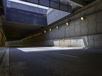 a dark parking space with concrete floors and overhead lighting on top of the garage wall