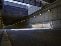 a dark parking space with concrete floors and overhead lighting on top of the garage wall