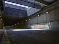 a dark parking space with concrete floors and overhead lighting on top of the garage wall