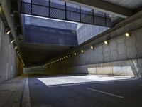 a dark parking space with concrete floors and overhead lighting on top of the garage wall