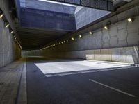 a dark parking space with concrete floors and overhead lighting on top of the garage wall