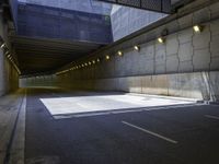 a dark parking space with concrete floors and overhead lighting on top of the garage wall