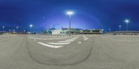 a fish eye view of an airport at night with lights shining on the road and buildings