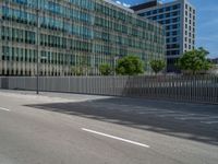 a man is on the sidewalk outside of a large office building with a wooden fence