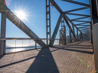 the sun is shining through the windows on a bridge over a lake of water and there are metal beams running across it