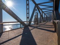 the sun is shining through the windows on a bridge over a lake of water and there are metal beams running across it