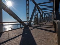 the sun is shining through the windows on a bridge over a lake of water and there are metal beams running across it