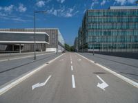 a road with white arrows that are on each side of it with a building in the background