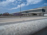 the sky is blue and has clouds and light poles, along side of it, a parking lot