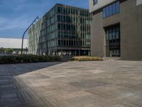 a concrete walkway and building with many windows and a sidewalk that is not made up