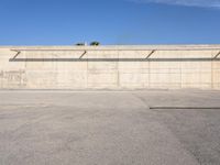 a long cement building has a blue sky above it and is empty in the background