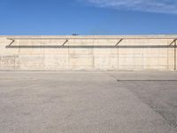 a long cement building has a blue sky above it and is empty in the background