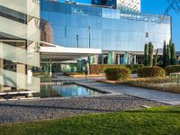 a large glass building with many windows on each of it's sides is surrounded by green grass and trees