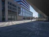 a very large modern looking building with many windows and a person standing outside on the sidewalk