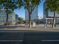 an empty street in front of a building and trees on the other side of the road