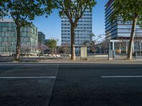 an empty street in front of a building and trees on the other side of the road