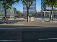 an empty street in front of a building and trees on the other side of the road