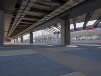 a picture of the underside of a train station on tracks, with lots of empty and concrete