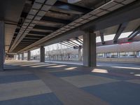 a picture of the underside of a train station on tracks, with lots of empty and concrete