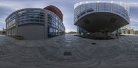 a circular image of a building in front of it's glass facade, showing the courtyard and circular view in the distance