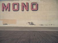 a woman walking on a sidewalk holding her luggage next to a wall with the word monono written on it