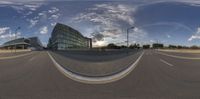 a 360 - view picture of an empty road with building in the background and street lamps lining either side of it