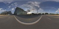 a 360 - view picture of an empty road with building in the background and street lamps lining either side of it