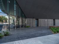 there is a courtyard outside and trees around it next to the building with glass walls