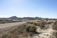 an empty road in a wide open plain of land near mountains and water on a sunny day