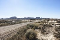 an empty road in a wide open plain of land near mountains and water on a sunny day