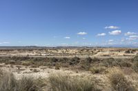 an empty road in a wide open plain of land near mountains and water on a sunny day