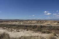 an empty road in a wide open plain of land near mountains and water on a sunny day