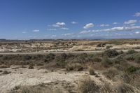 an empty road in a wide open plain of land near mountains and water on a sunny day