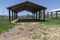 a barn with an open roof is located in a field of dry grass and a grassy area behind it